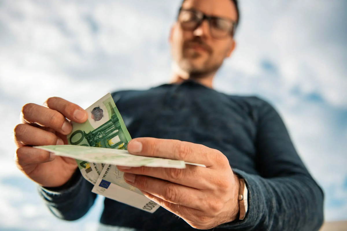 A person counting euro banknotes, symbolizing changing financial priorities and the shift towards essential spending in today's economy