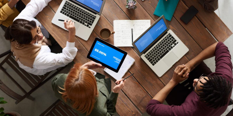 Image showing a team collaborating around a table with laptops and tablets